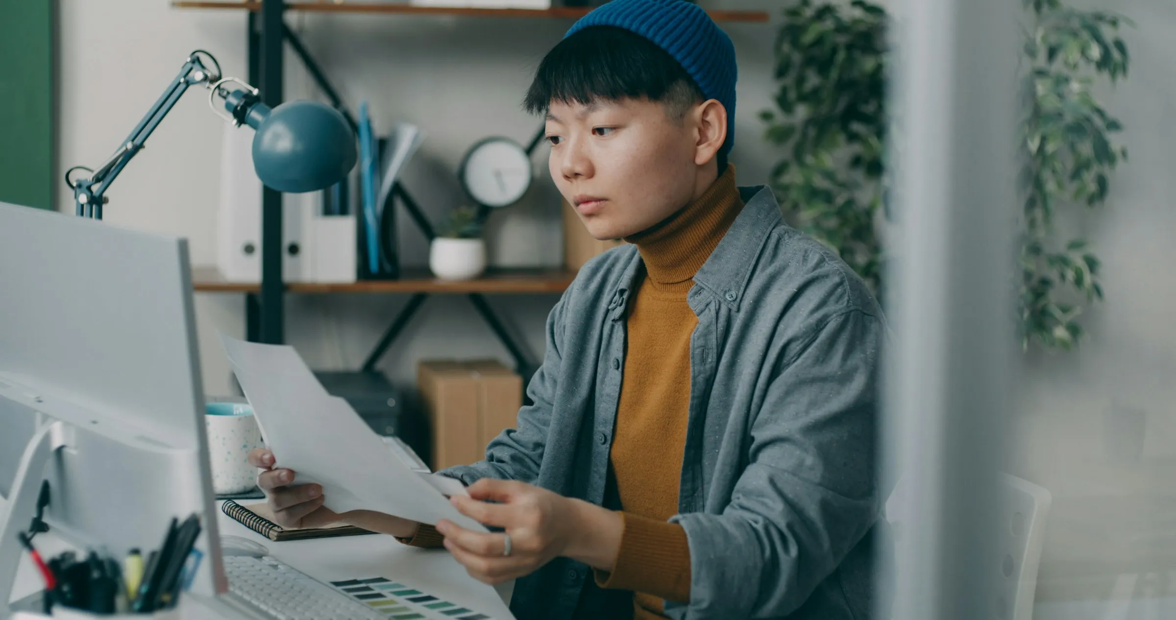 A person reading through a printed document at their desk