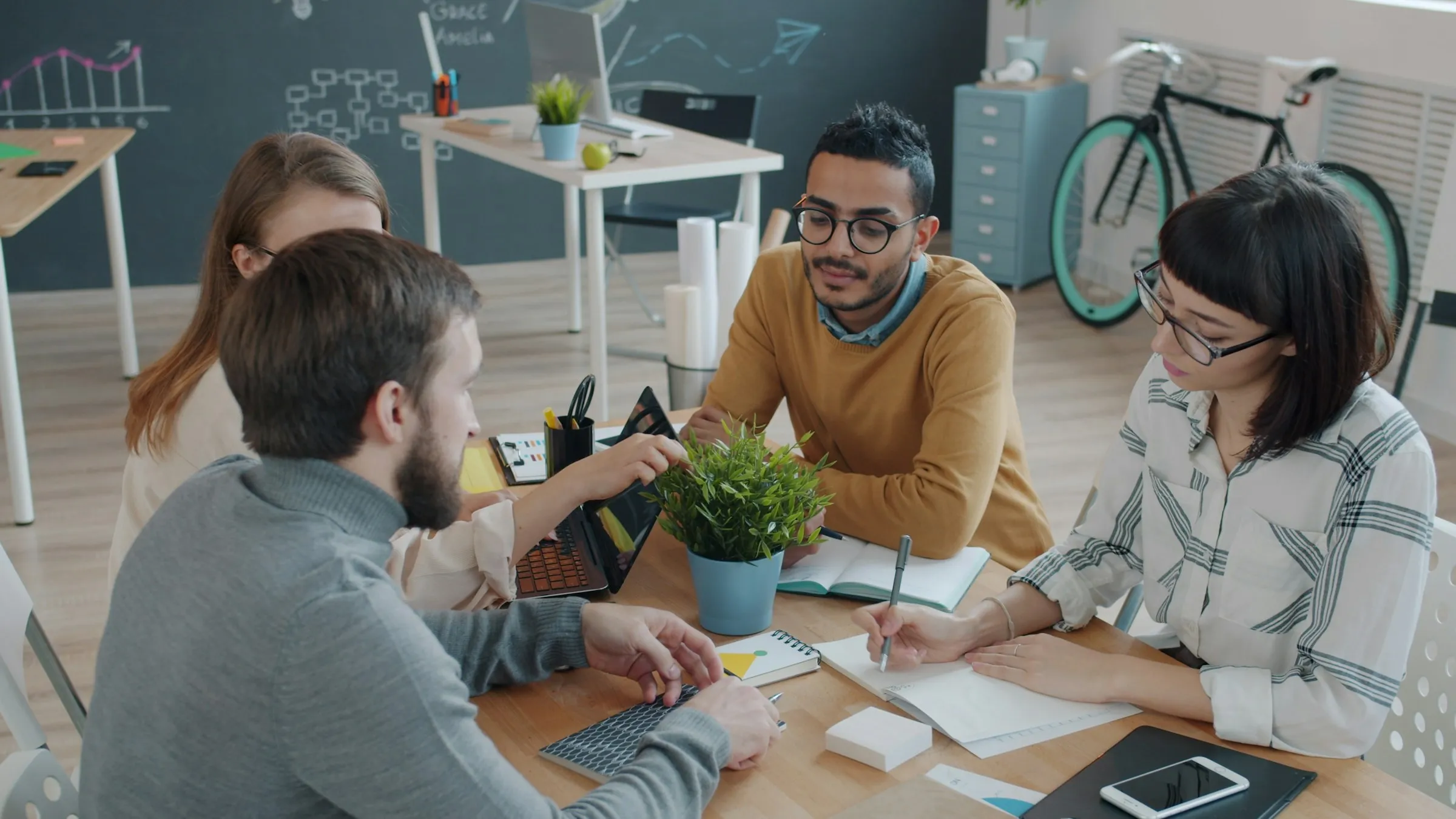 A small team working around a table with notebooks and a laptop